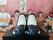 Front view highlighting the glossy dark blue toe panels, white uppers, and contrasting outsole colors.