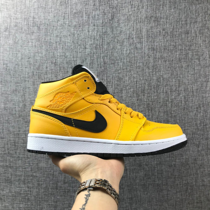 Side view of a yellow and black Jordan Air Jordan 1 Mid sneaker with a white midsole.