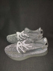Pair of silver-gray knit sneakers shown from an angled front view with translucent ribbed soles.