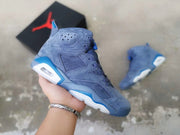 Close-up view of a blue and dark navy high-top basketball sneaker held in hand, showing perforated panels and visible heel cushioning.