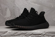 Front three-quarter view of black low-top knit-style sneakers with matching laces.