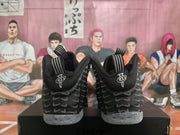 Rear view showing black heel panels, gray Swoosh-style graphics, pull tabs, and translucent speckled outsoles.