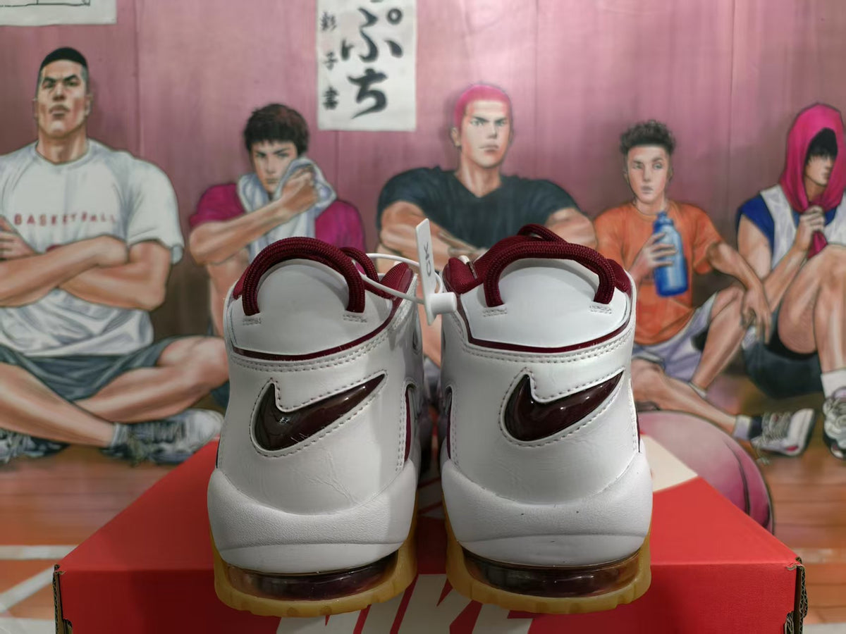 Rear view of white Nike high-top sneakers with burgundy Swoosh accents and translucent gum-colored outsoles.