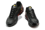 Front view of black Nike Air Max Plus sneakers with red side accents
