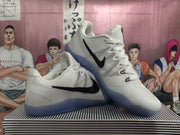 Pair of white Nike basketball shoes showing black side logos and translucent blue outsoles.