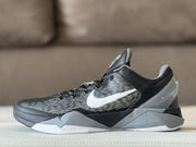 Side profile of a black, grey and white Nike Kobe 7 sneaker with a striped upper and white Swoosh.