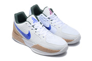 Angled view of the white and blue Jordan sneaker pair with tan-gold midsoles and dark green collar lining.