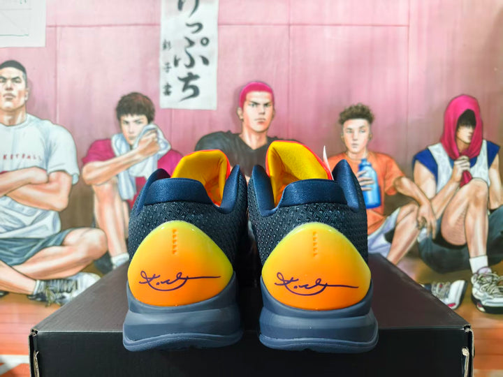 Rear view of navy Nike Kobe basketball shoes with yellow-orange heel panels and dark gray soles.