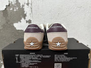 Rear view of cream Converse trainer-style sneakers with plum heel panels and gum-colored soles