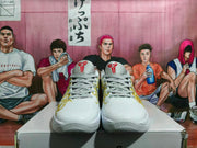 Front view of white Nike basketball sneakers with gray laces, red tongue logos, and gold side detailing.