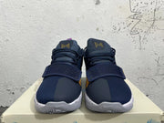 Front view of navy Nike PG 1 shoes showing forefoot straps, yellow lace accents and speckled midsoles