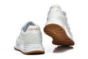 Rear and outsole views of white Prada sneakers with gum-colored tread.