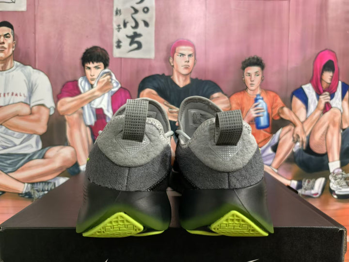 Rear view of gray and black Nike sneakers with lime-green outsole accents