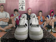 Front view of white and black high-top sneakers showing white laces, mesh panels, grey toe overlays, and tongue logos.