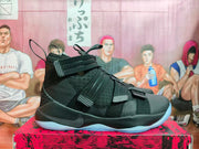 Side view showing the black upper, multiple straps, heel pull loop, and light blue outsole.