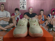 Front view of the pair showing lace-up closures, perforated upper panels, red tongue branding, and pink-toned toe outsoles.