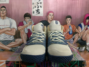 Front view of the off-white and navy basketball sneakers showing the laces, padded tongues, patterned quarter panels, and dark outsole.