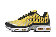 Side view of yellow patterned Nike Air Max Plus sneakers with visible cushioning windows.