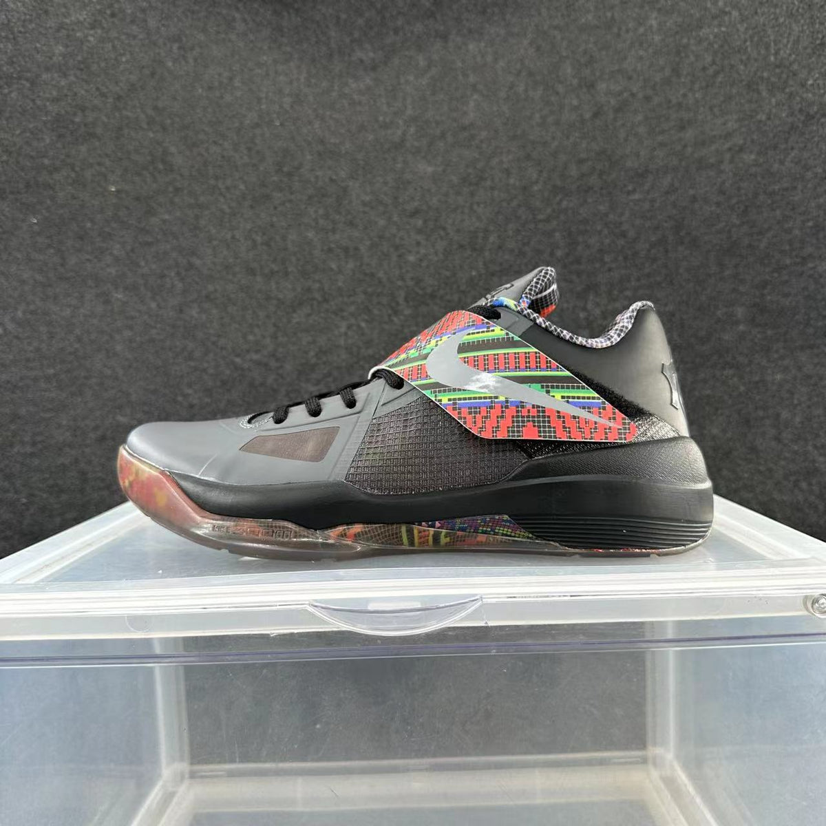 Side view of a black and gray Nike Kobe basketball shoe with multicolor geometric accents.