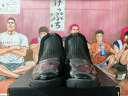 Top-front view of the sneaker pair showing textured tongues, glossy toe panels, black construction, and red details.