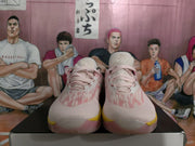 Front view showing the pink laces, white and pink upper, yellow outsole accents, and tongue details.