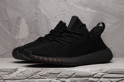 Front three-quarter view of a black lace-up sneaker with a textured upper and rounded toe.