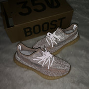 Flash-lit view of taupe-pink sneakers showing reflective details, with a box marked 350 BOOST in the background.
