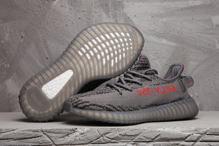 Pair of dark grey and black patterned Yeezy 350 V2-style sneakers showing the ribbed outsole and red side lettering.