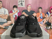 Front view of the pair showing black mesh-like uppers, black laces, tongue branding, and gray toe and outsole details.