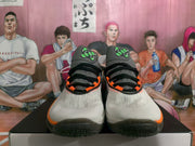 Front view showing the paired white Nike basketball sneakers with black laces and bright orange trim.