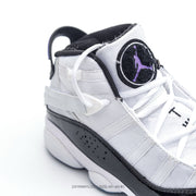 Close-up of the white tongue, black-and-purple tongue emblem, laces and ankle strap.