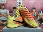 Angled view of yellow and orange Nike basketball shoes with black Swooshes
