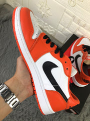 Side view showing the black side logo, orange overlays, white midsole and orange outsole.