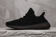 Side profile of the black sneaker with a textured upper, heel pull tab, and ribbed sole.
