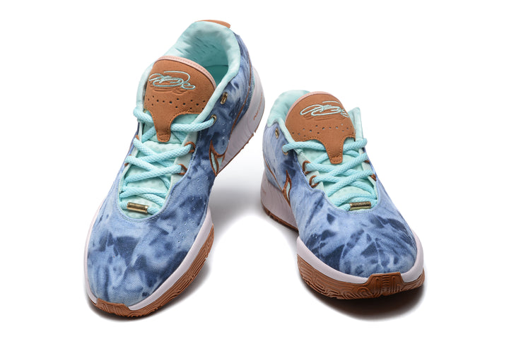 Pair of blue Nike low-top sneakers shown from the front, with pale aqua laces, brown tongue details, white midsoles, and gum-colored outsoles.