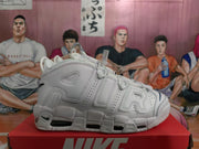 Side profile of a white Nike sneaker with layered AIR lettering, perforated panels and visible sole air windows.