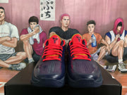 Front view of dark blue basketball sneakers with red laces, red tongues, perforated toe areas, and visible tongue logos.
