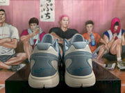 Rear view showing the gray heel panels, padded collars, blue signature-style details, and light-colored outsoles.