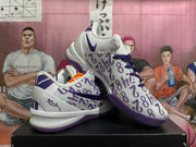 Angled view of white and purple Kobe basketball shoes showing the patterned upper and outsole.