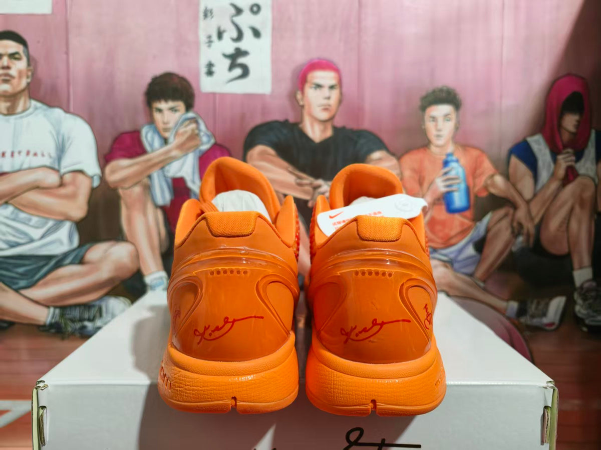 Rear view of orange Nike basketball sneakers displayed on a shoe box.
