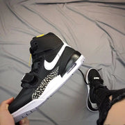 Side view emphasizing the white Swoosh, elephant-print panel, black upper, and visible heel cushioning window.