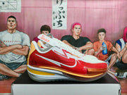 Side profile of a red and white Nike basketball sneaker showing the textured red upper, white overlays, gold detail, and layered sole.