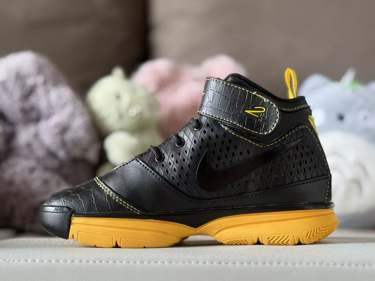 Side view of black and yellow Nike Kobe 2 kids' high-top sneakers.