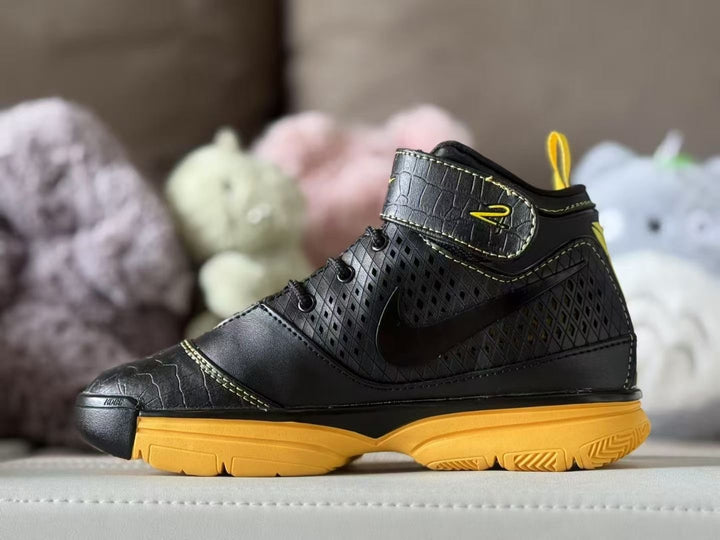 Side view of black and yellow Nike Kobe 2 kids' high-top sneakers.
