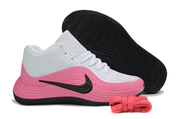 White and pink Nike basketball sneaker shown beside its patterned black outsole.
