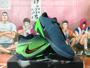 Angled view of navy and bright green Nike basketball shoes with textured uppers and patterned soles.