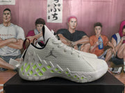 Side profile of a white Jordan basketball sneaker with neon green geometric accents, a visible Jumpman logo, and a patterned rubber outsole.