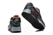 Nike Air Max 90 sneakers shown from the rear and outsole, with orange collar lining.