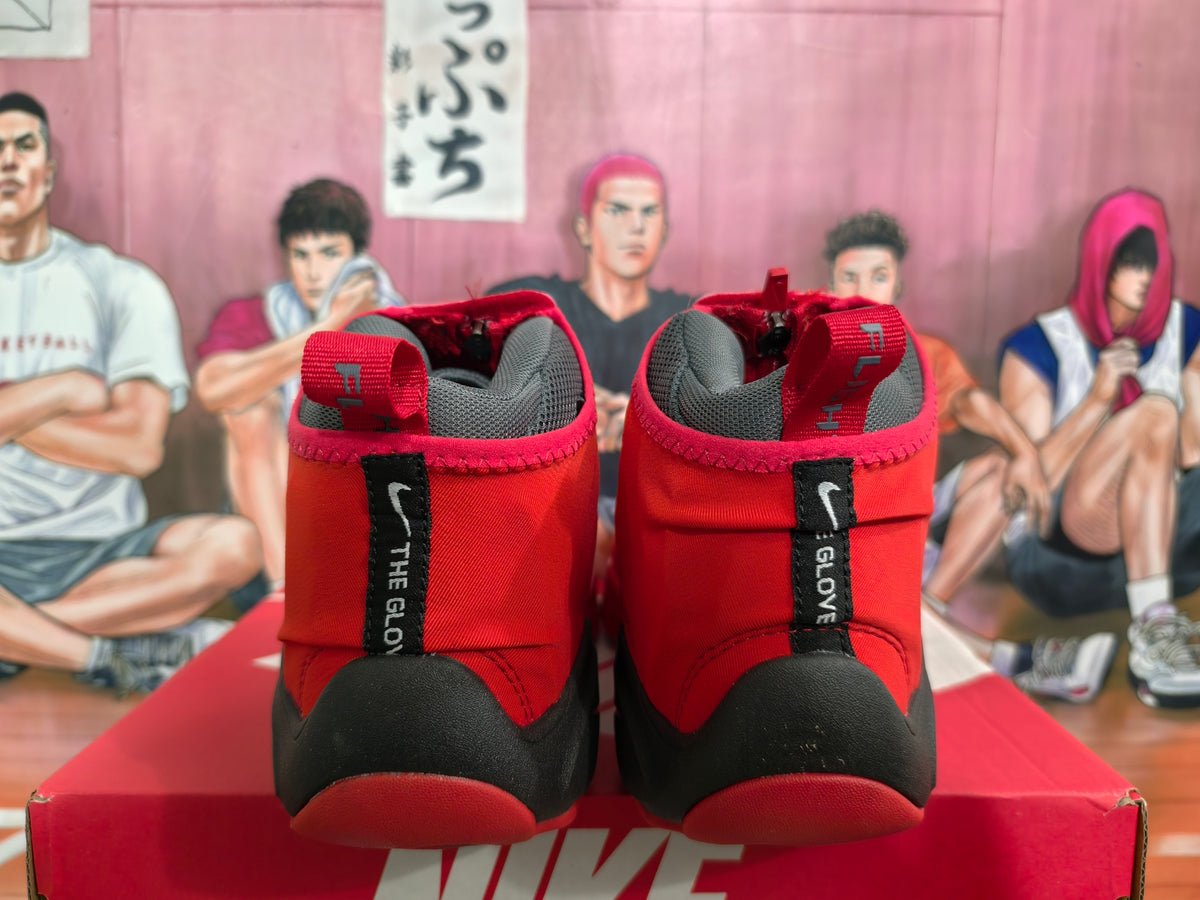 Rear view of red and black Nike high-top sneakers showing padded gray collars, heel pull tabs, and vertical heel branding.
