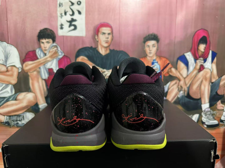 Rear view of black Nike Kobe basketball shoes with burgundy signature-style heel graphics, speckled heel panels, gray midsoles, and volt outsoles.